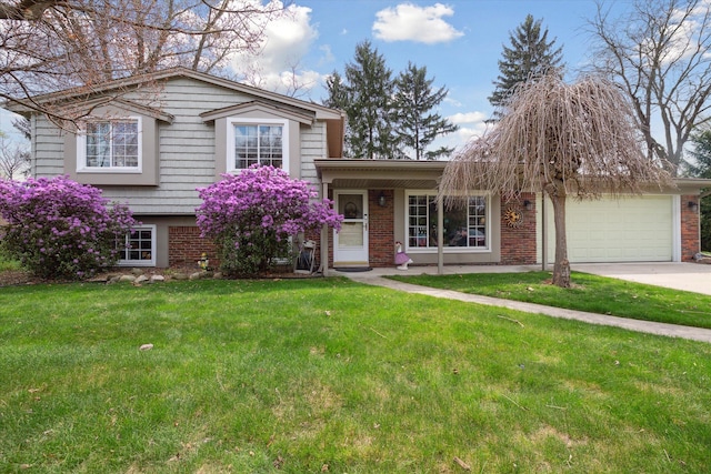tri-level home with a garage, concrete driveway, a front lawn, and brick siding