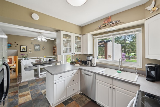 kitchen with stainless steel dishwasher, a sink, electric stove, white cabinetry, and stone tile floors