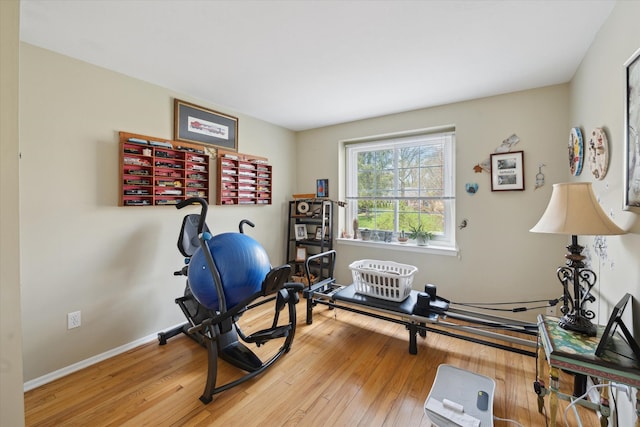 exercise room with baseboards and wood-type flooring