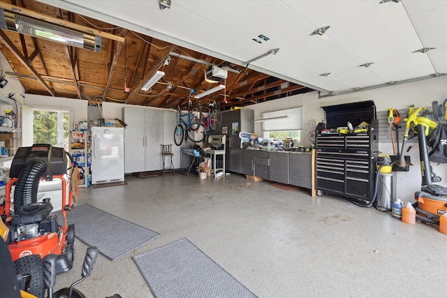 garage featuring freestanding refrigerator, a workshop area, and a garage door opener