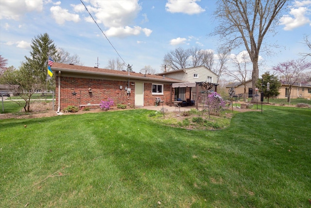 rear view of house with a patio, a lawn, and brick siding