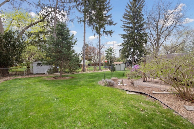 view of yard featuring an outbuilding, fence, and a storage shed