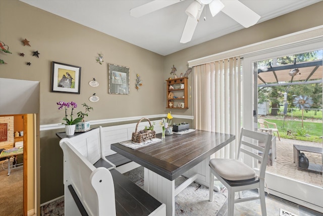 dining area featuring a ceiling fan and a wainscoted wall