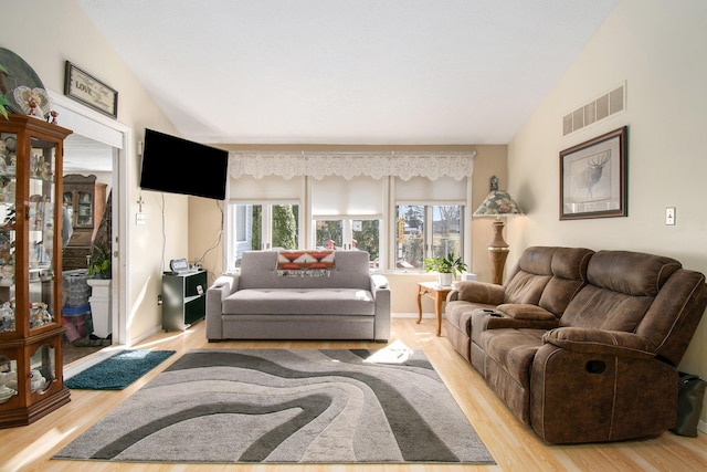 living room featuring lofted ceiling, visible vents, and light wood-style floors