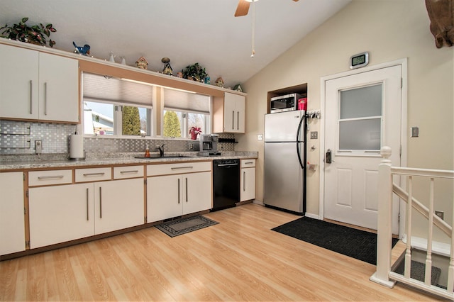 kitchen featuring tasteful backsplash, stainless steel appliances, vaulted ceiling, a sink, and light wood-type flooring