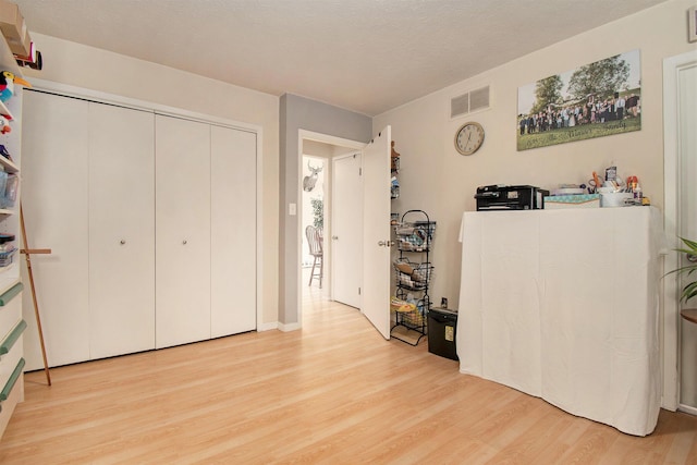 bedroom with visible vents, light wood-style floors, and a closet