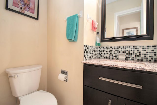 half bath with toilet, backsplash, and vanity