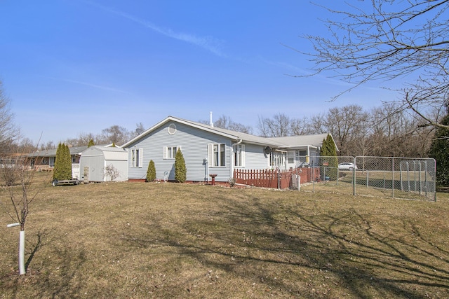 rear view of house with an outbuilding, a storage shed, a yard, and fence