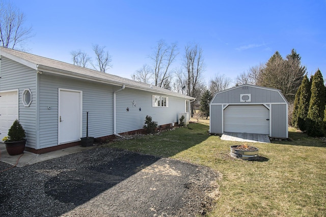 exterior space featuring an outdoor fire pit, an outdoor structure, a storage unit, and a front yard