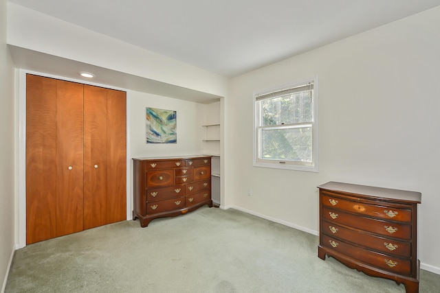 bedroom featuring a closet, light carpet, and baseboards