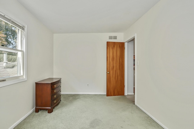 unfurnished room featuring baseboards, visible vents, and light carpet