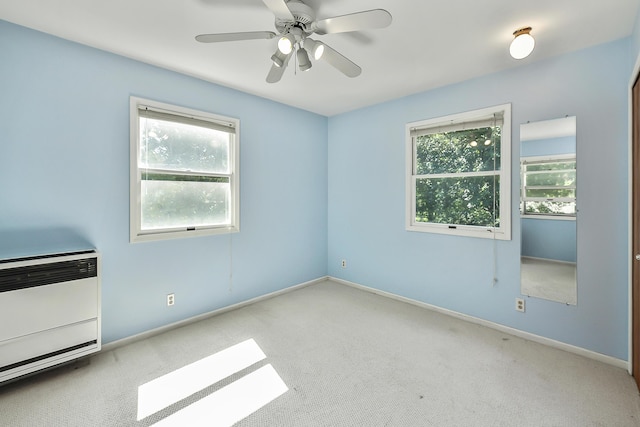 carpeted empty room with ceiling fan, baseboards, and plenty of natural light