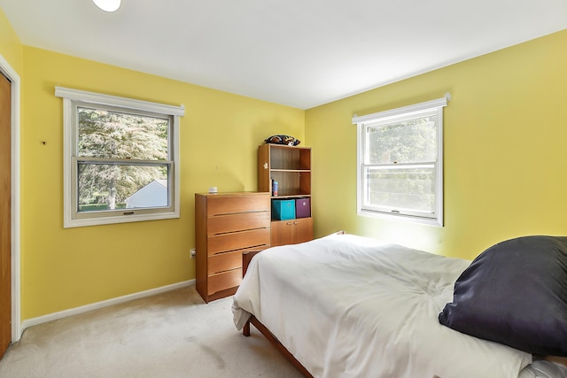 bedroom with baseboards and light carpet