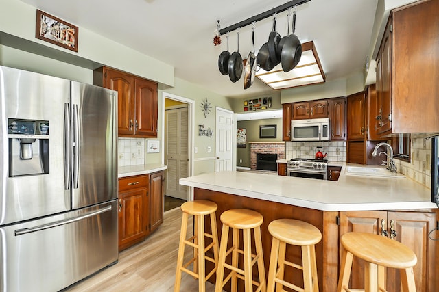 kitchen featuring decorative backsplash, light wood-style flooring, a sink, stainless steel appliances, and light countertops