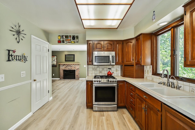kitchen with decorative backsplash, light wood-style flooring, a sink, appliances with stainless steel finishes, and light countertops