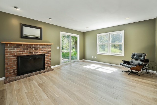 unfurnished living room featuring wood finished floors, baseboards, visible vents, and a brick fireplace
