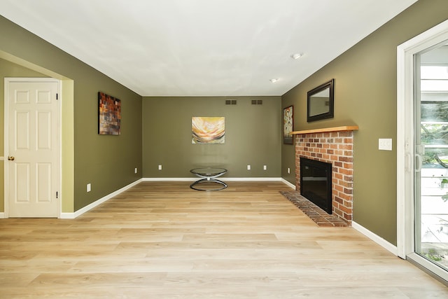 unfurnished living room with a brick fireplace, baseboards, and light wood-style floors