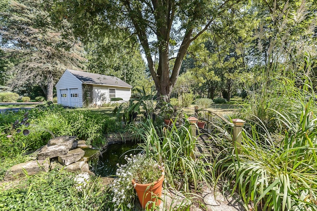 view of yard with an outdoor structure, a small pond, and a garage