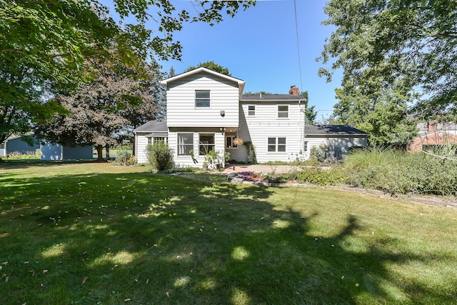 back of property with a chimney and a lawn