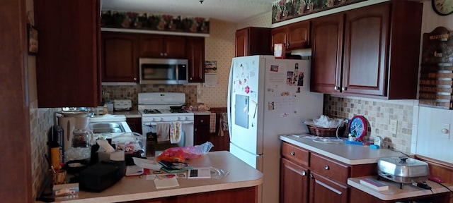 kitchen featuring light countertops, a sink, tasteful backsplash, and white appliances