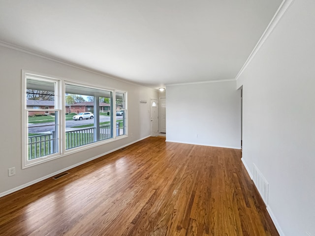 unfurnished room with crown molding, baseboards, wood finished floors, and visible vents