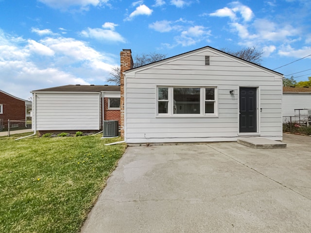 back of house featuring central AC, fence, a chimney, a patio area, and a lawn
