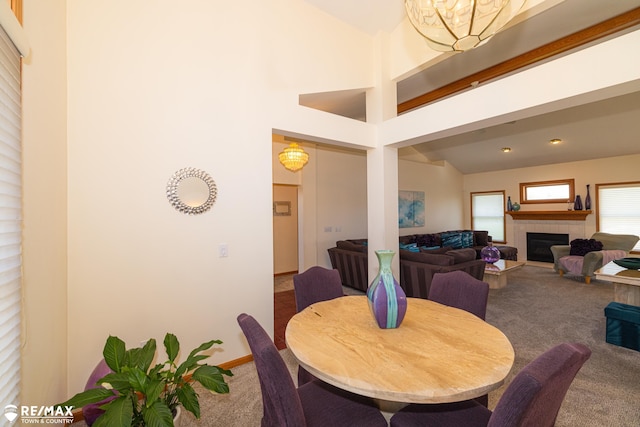 7077 Crosswinds Dr, Swartz Creek, MI 48473 - dining room with baseboards, an inviting chandelier, a tile fireplace, vaulted ceiling, and carpet