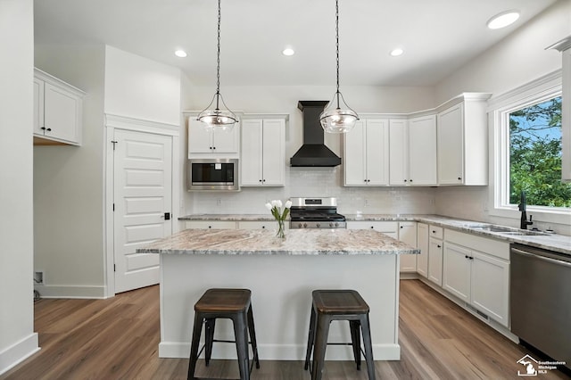 552 Central Park Blvd, Monroe, MI 48162 - kitchen with appliances with stainless steel finishes, wall chimney exhaust hood, tasteful backsplash, white cabinets, and recessed lighting