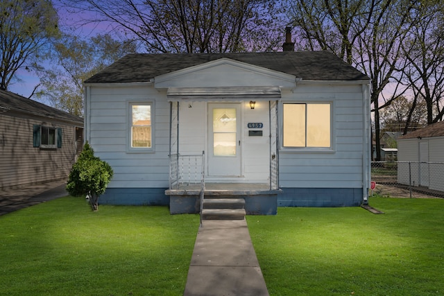 view of front of house with fence, a front lawn, and roof with shingles