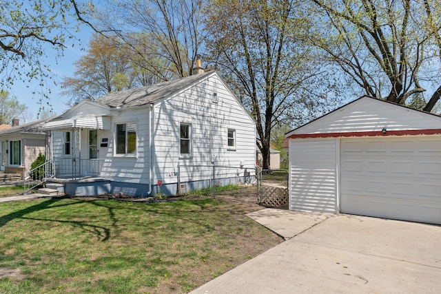 view of home's exterior featuring driveway, an outdoor structure, a shingled roof, a lawn, and a garage