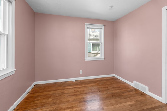 spare room with visible vents, wood finished floors, and baseboards