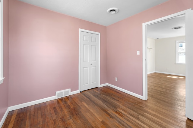 empty room featuring baseboards, visible vents, and dark wood-style flooring