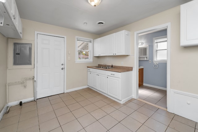 kitchen featuring electric panel, white cabinetry, and plenty of natural light