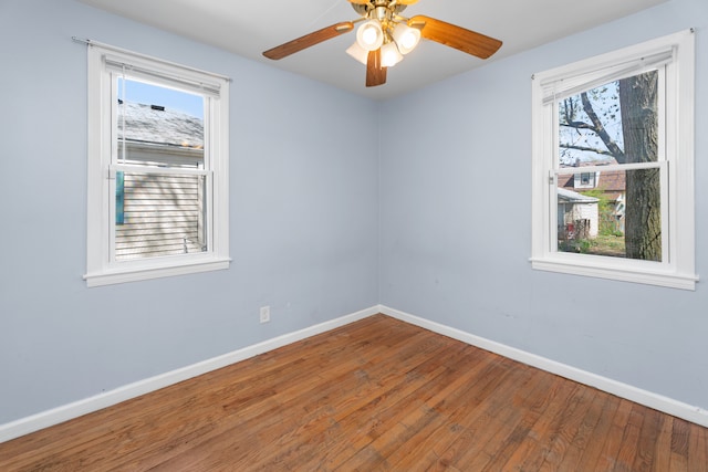 empty room with a ceiling fan, hardwood / wood-style floors, a healthy amount of sunlight, and baseboards