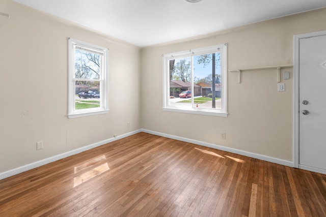 spare room with a healthy amount of sunlight, hardwood / wood-style floors, and baseboards