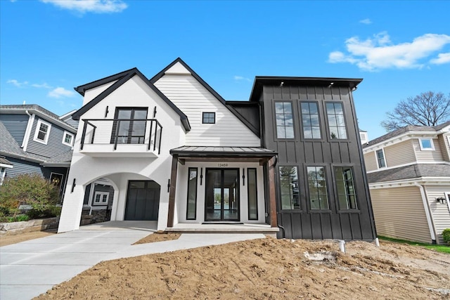 13459 Haddon St, Fenton, MI 48430 - view of front facade featuring a standing seam roof, board and batten siding, concrete driveway, and a balcony
