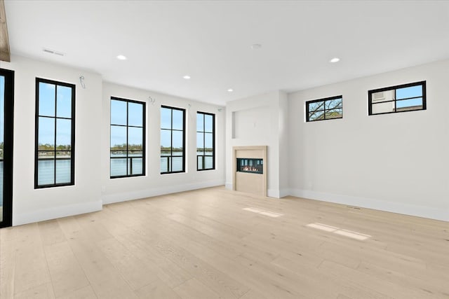 13459 Haddon St, Fenton, MI 48430 - unfurnished living room with baseboards, visible vents, a glass covered fireplace, and light wood-style floors