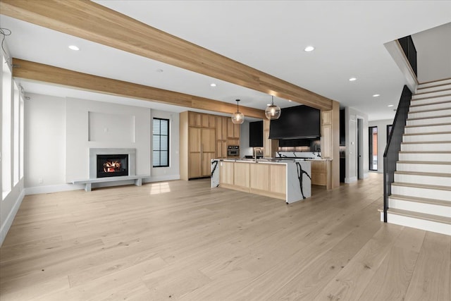 13459 Haddon St, Fenton, MI 48430 - kitchen featuring a center island with sink, beam ceiling, open floor plan, light brown cabinets, and light wood-style flooring