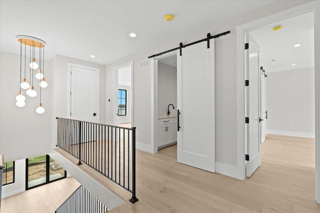 13459 Haddon St, Fenton, MI 48430 - hallway featuring light wood-style floors, baseboards, a barn door, and visible vents