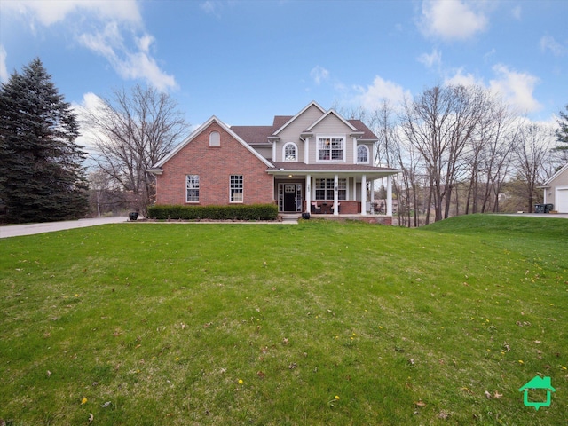 view of front of property with covered porch, brick siding, and a front yard