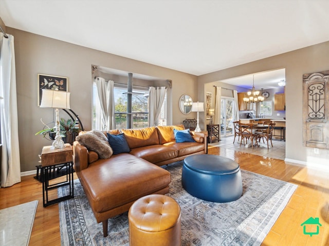 living area featuring an inviting chandelier, light wood-style flooring, and baseboards