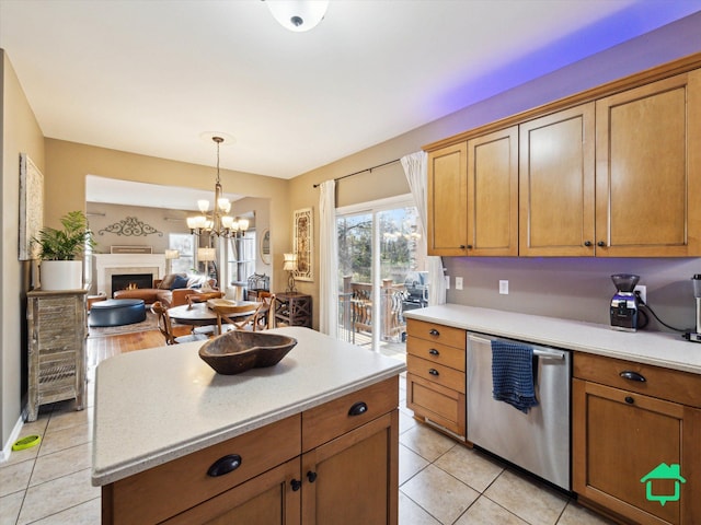 kitchen featuring light tile patterned floors, dishwasher, a lit fireplace, and light countertops