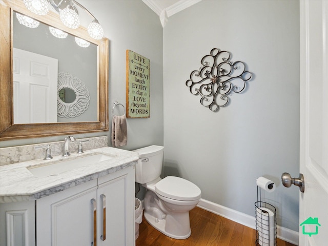 bathroom with baseboards, toilet, ornamental molding, wood finished floors, and vanity