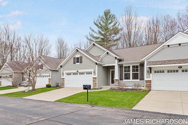 craftsman-style home featuring driveway, a garage, a front yard, and stone siding