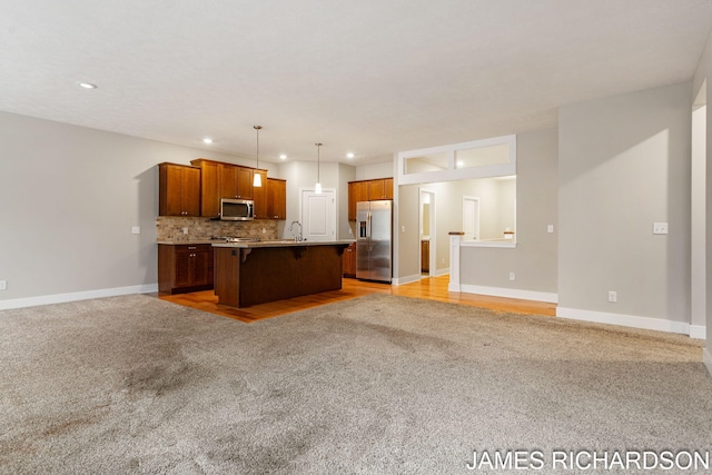 kitchen with stainless steel appliances, open floor plan, a kitchen breakfast bar, and light colored carpet