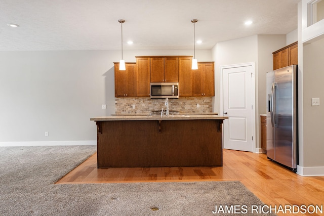 kitchen featuring hanging light fixtures, baseboards, stainless steel appliances, and tasteful backsplash