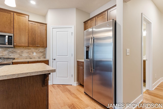 kitchen featuring recessed lighting, light wood-style flooring, stainless steel appliances, light countertops, and backsplash