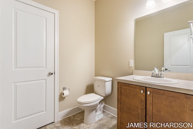 bathroom with toilet, vanity, and baseboards