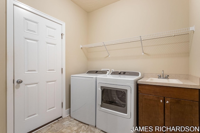 clothes washing area with baseboards, cabinet space, washing machine and clothes dryer, and a sink