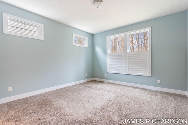 carpeted spare room featuring baseboards and visible vents